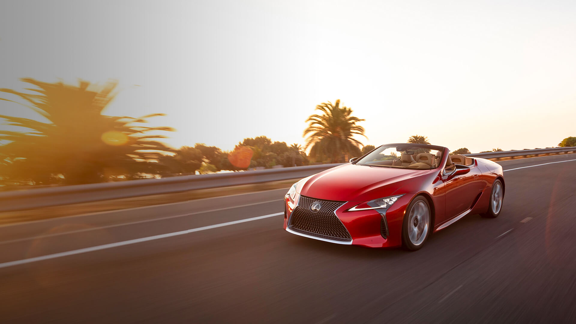 Red Lexus LC Convertible being driven on the road with the top down.